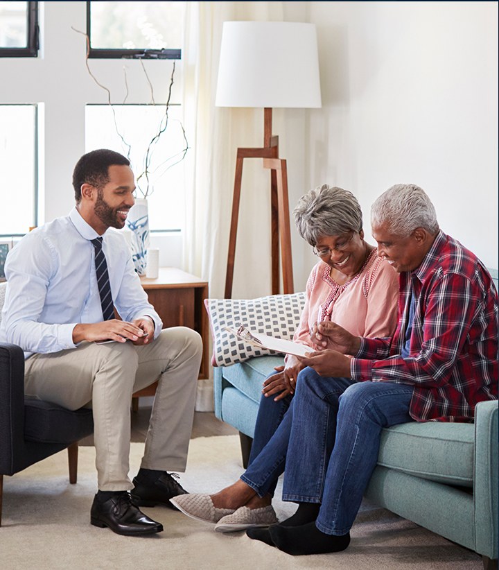 Attorney sitting with an older couple in their home, reviewing paperwork together