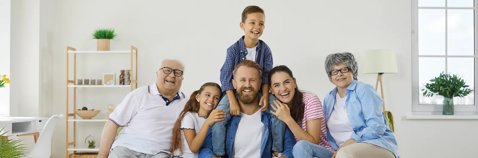 Three generations of a family sitting together on a sofa in a bright living room