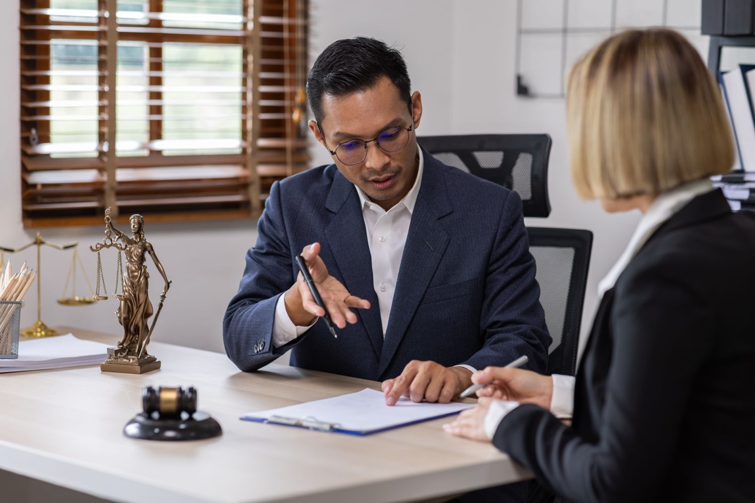 Attorney explaining a document to a client, scales of justice on the desk