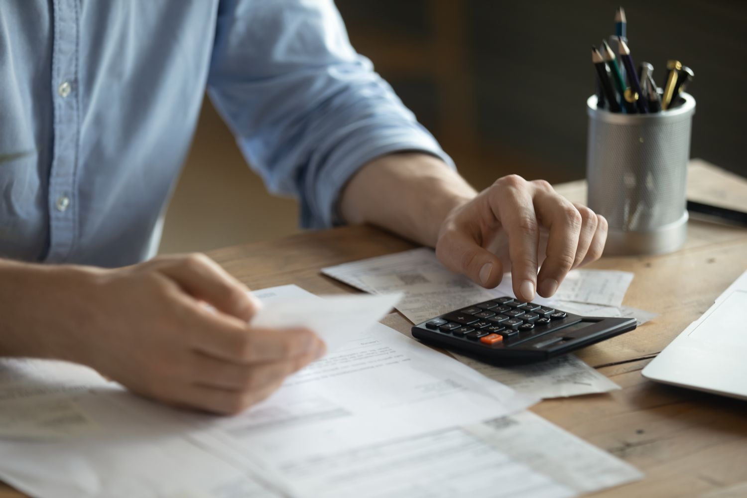 Hands using a calculator beside financial paperwork