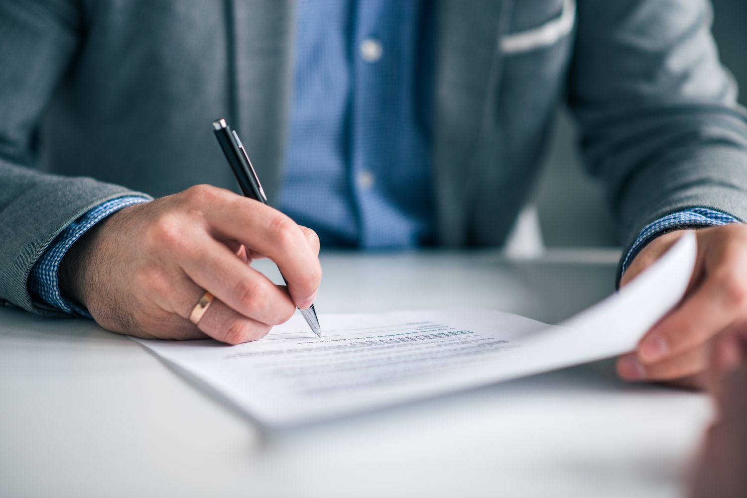 Close-up of a hand signing a contract at a desk