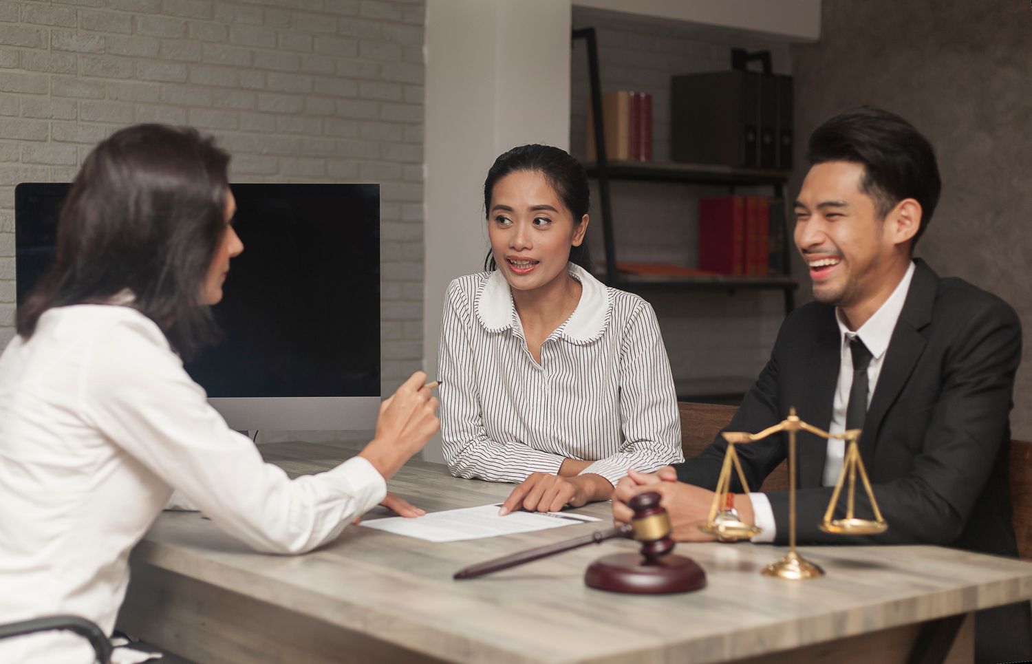 Family meeting an attorney across a desk, scales of justice in the foreground