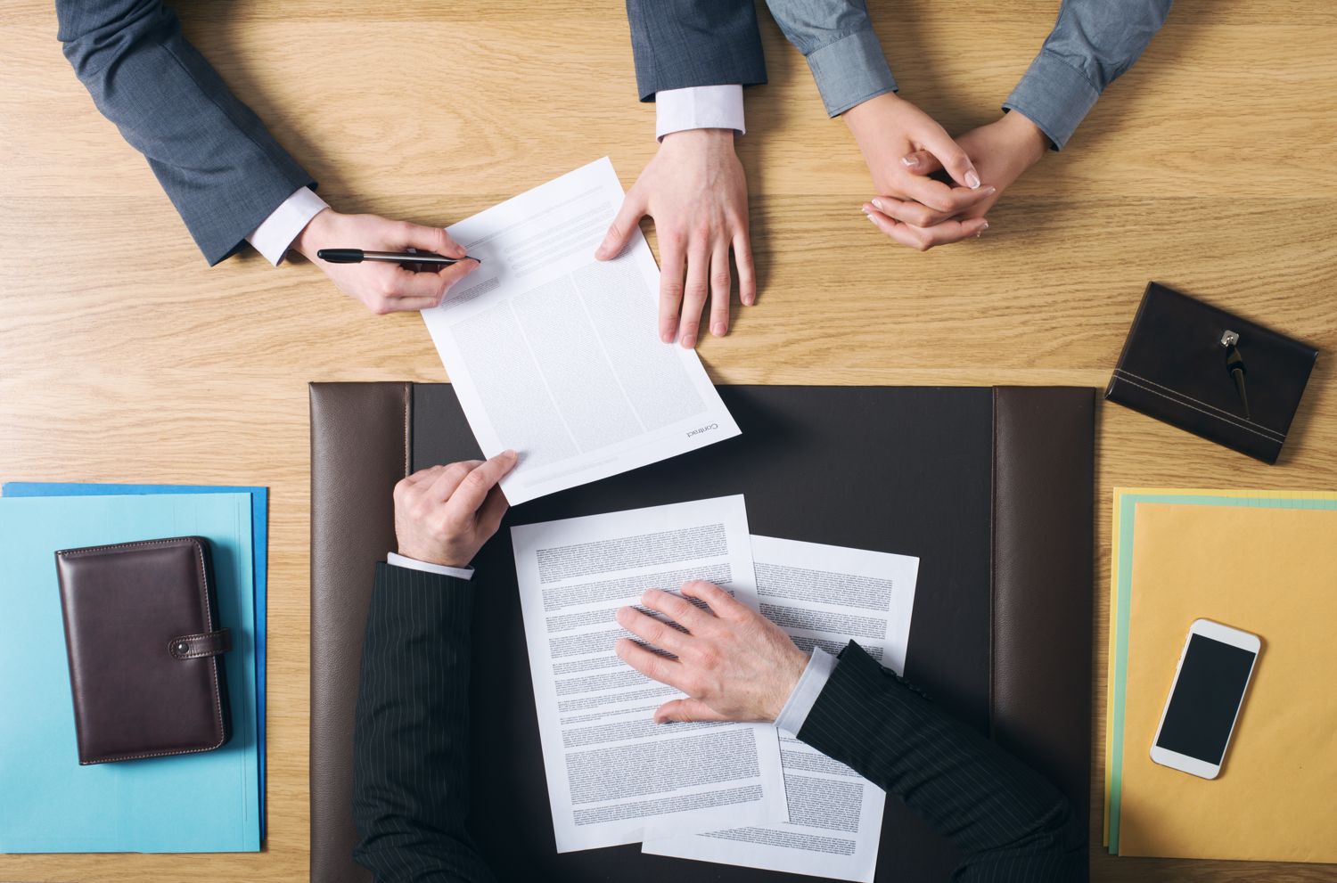 Overhead view of two people signing paperwork at a desk
